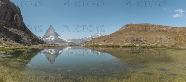 The snow-capped mountains rise majestically above a calm lake, where their towering reflections