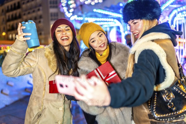 Three happy female friends are taking a selfie with a christmas gift at a christmas market,