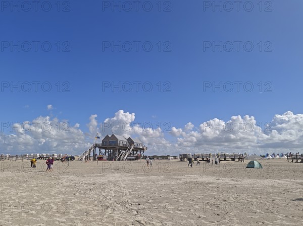 Wide North Sea beach with pile dwellings, blue sky, white clouds, summer, sun, beach chairs, on the