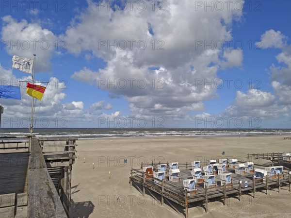 North Sea beach, blue sky, white clouds, summer, sun, sand, beach chairs on pedestal, flags, on the