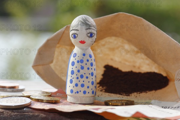 Pretty female wooden cone figure with coins and banknote in front of filter bag with coffee North