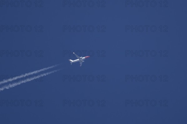 Boeing 737 jet passenger aircraft of Norweign Air with a vapour trial or contrail behind flying in