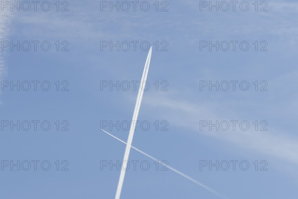 Two jet passenger aircraft with vapour trails or contrails flying in a blue sky crossing making a