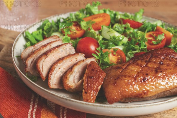 Delicious grilled duck breast served with fresh garden salad and cherry tomatoes at a rustic dining