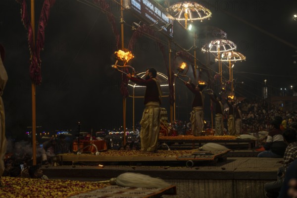Hindu priest performing the Aarti ritual, holding a burning oil lamp, at the Ganges, Bangali Tola,