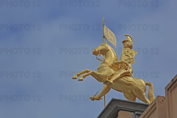 Golden equestrian figure with city coat of arms and flag, monument to city founder Henry the Lion,