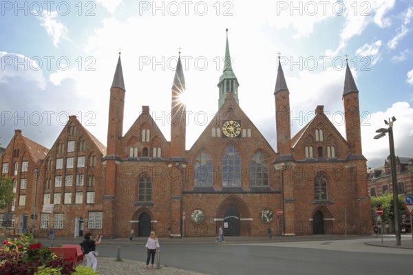 Holy Ghost Hospital backlit with pointed towers, Brick Gothic, Brick building, Old Town, Lübeck,