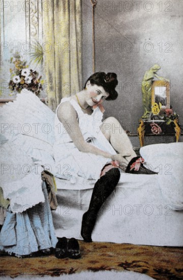 Female nude from around 1899, erotic postcard, playgirl, woman putting on stockings in the bedroom,