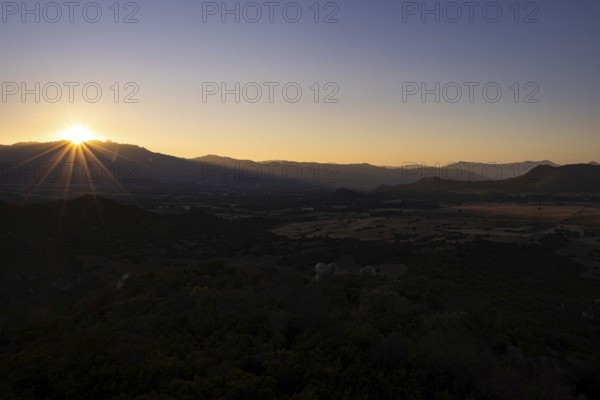 The sun sets behind the mountains on the Mediterranean island of Sardinia, Monte Nai, Costa Rei,