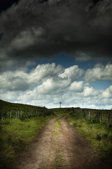 A winding dirt road leads the eye to a solitary cross. Cézallier, Auvergne Volcanoes Regional