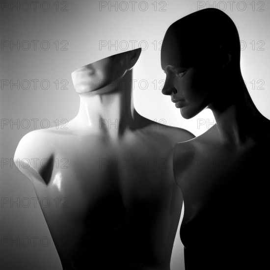 Two stylized mannequins stand closely together, featuring smooth surfaces and abstract shapes.