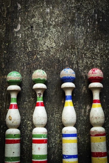 Vibrant wooden bowling pins stand aligned against a weathered surface, inviting players to enjoy a