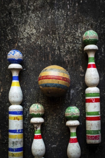 A classic bowling game set showcases worn wooden pins in vibrant colors and a striped ball,