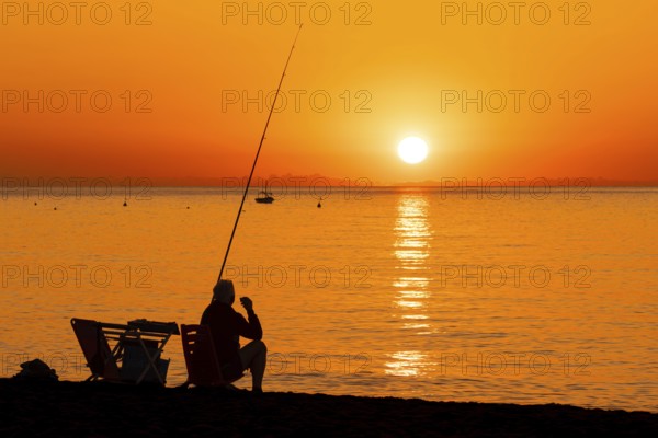 A man fishing shortly after sunrise on the Costa Rei, a stretch of coastline on the Italian island
