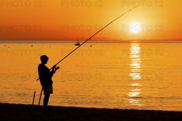 A boy fishing shortly after sunrise on the Costa Rei, a coastline of the Italian island of