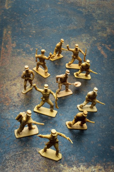 Small toy soldiers are positioned in a playful arrangement on a rough surface. Their poses suggest