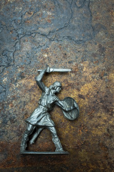 A detailed warrior figure stands ready for battle, gripping a sword in one hand and a shield in the