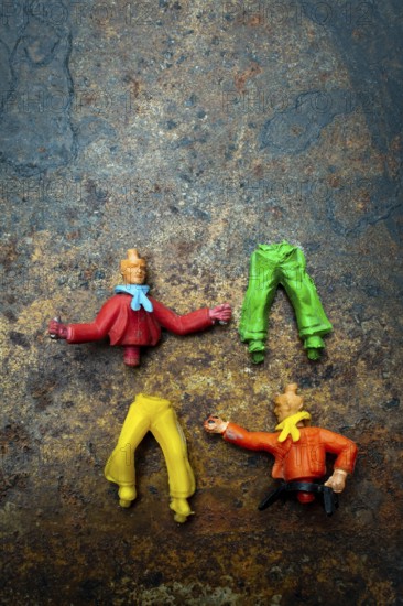Four vibrant plastic figures with missing heads and different clothing pieces are creatively