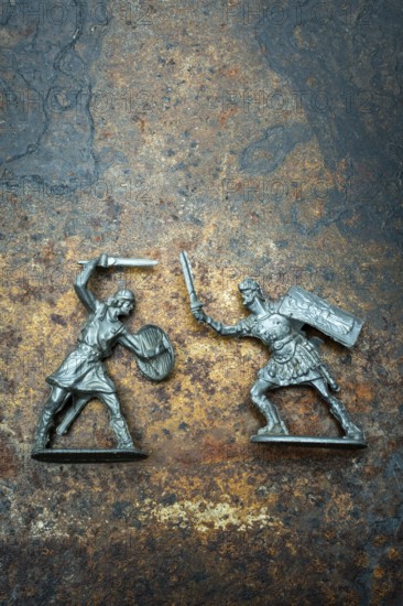 Two plast miniature figures depict a warrior with a shield and sword facing off against a roman