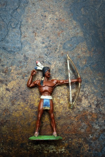 A bright plastic toy archer stands poised with his bow drawn back, showcasing the figure of an