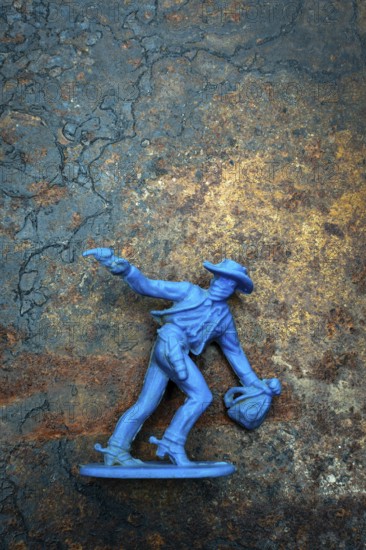 A bright blue cowboy figure stands firmly on a rugged surface, one hand raised with a pistol while