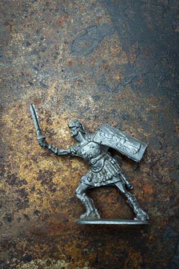 A roman soldier figure stands ready for combat, holding a sword in one hand and a shield in the