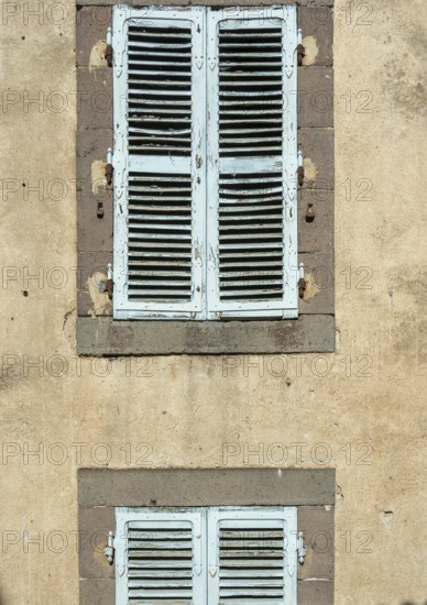 Two sets of vintage blue shutters add charm to a weathered wall, showcasing the beauty of rustic