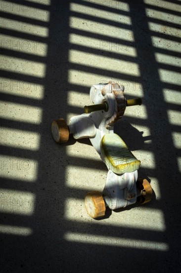 A vintage ride-on toy sits on a concrete surface, illuminated by sunlight streaming through a