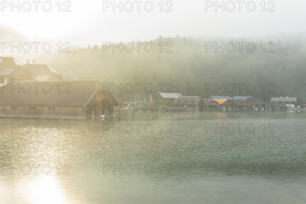 Mystical morning at Königssee in Schönau with boathouses. Sunrise and beautiful wafts of mist over