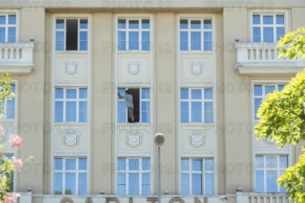 A window cleaner cleans a window and stands on the windowsill, Bratislava, Slovakia