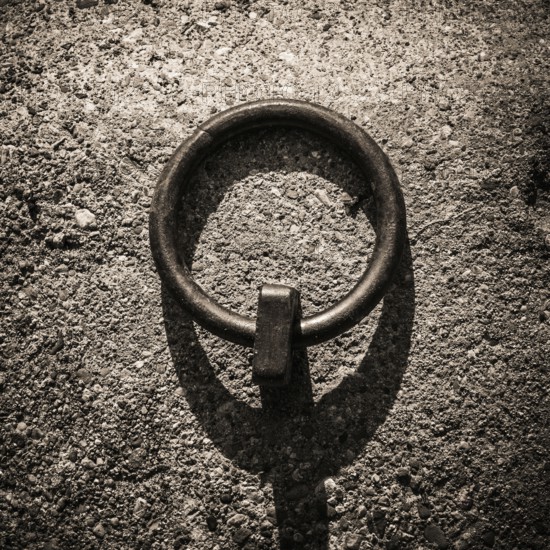 Mooring rings made of iron are embedded in the dockside, showcasing a rugged texture under soft