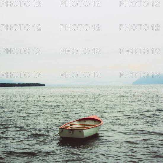 A rowing boat drifts quietly on the serene surface of Lake Geneva near Lausanne, Switzerland. The