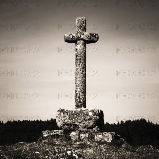 In the heart of Auvergne, a weathered stone cross rises majestically against a backdrop of