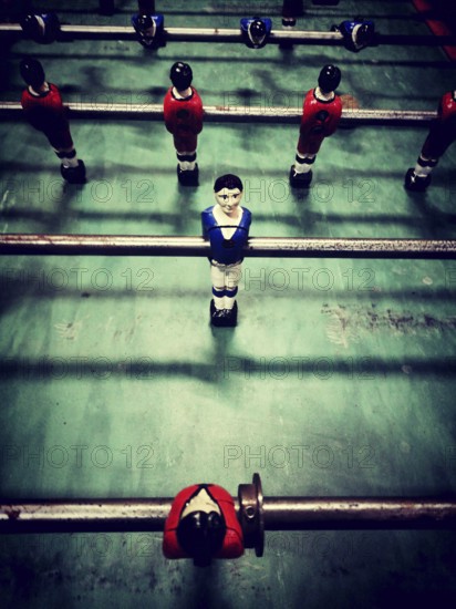 A lively table football game features diverse player figures in red, blue, and black, positioned on