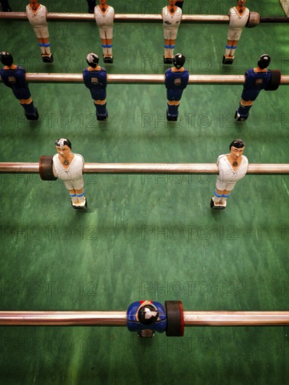 Players are set in a vintage table football game, ready for action. The colorful figures are