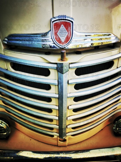 The front grille of a vintage truck features intricate chrome detailing with a prominent emblem.