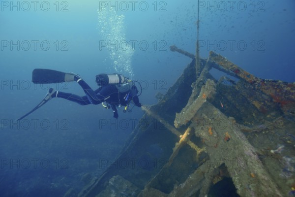 Diver floats near a shipwreck while air bubbles rise to the surface. Dive site wreck Michel C,