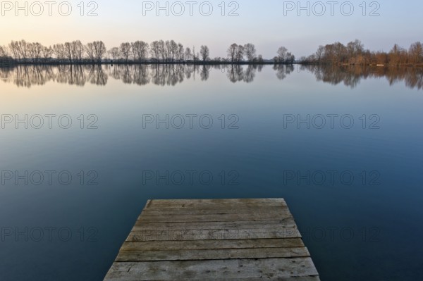Sunset at Moosinninger Weiher with wooden footbridge, quarry pond, fishing pond for carp,