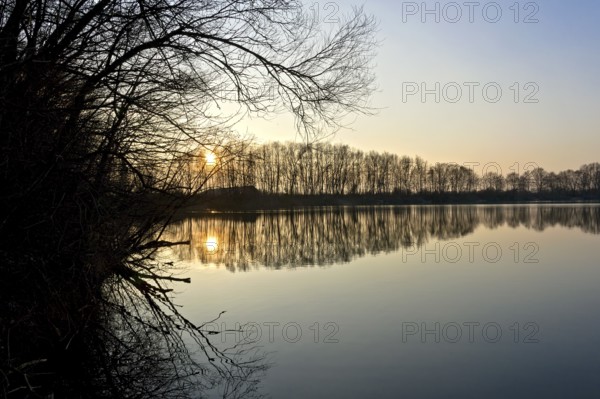 Sunset at Moosinninger Weiher, quarry pond, fish pond for carp, reflection of the trees on the