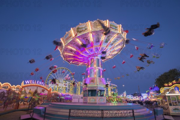 Brightly illuminated carousel at a night fair, chain carousel, spring festival, Cannstatter