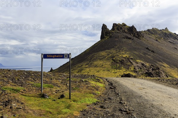 Gravel road with sign for place of interest, lava cave, Sönghellir lava tube, Stapafell mountain,