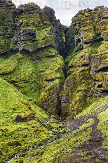 Moss-covered rock formation with entrance to the mystical lava cave, Sönghellir lava tube, Cave of