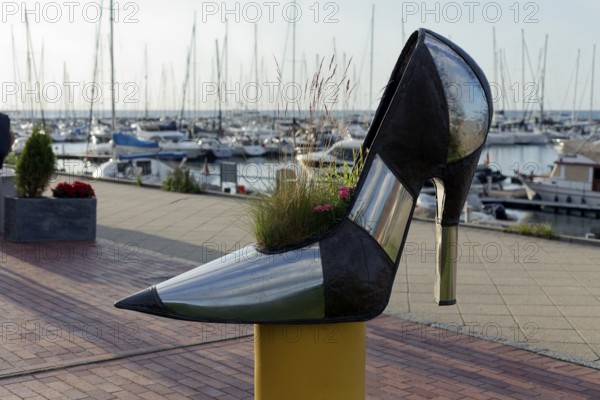 Oversized high-heeled shoe, planted with flowers, boutique on the beach promenade, Baltic resort
