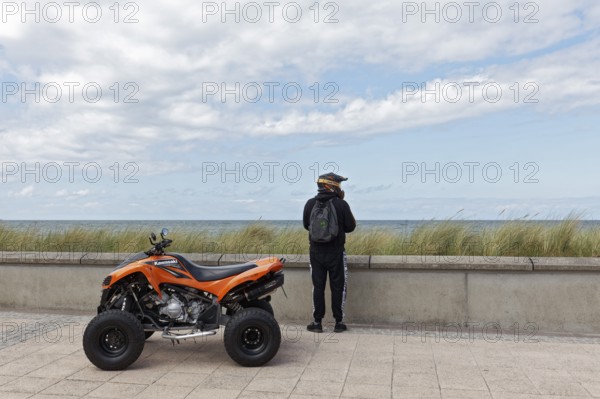 Motorcyclist with Kawasaki Quad Bike on the beach promenade, looking at the sea, Baltic resort