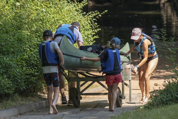 Family pushes canoe with canoe cart to the Alte Fahrt canal, Bolter Mühle, Mecklenburg Lake