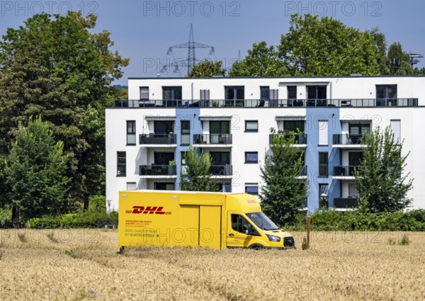 DHL parcel van, electric vehicle, on the way to a customer, rural, driving along a dirt track
