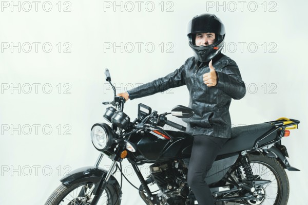 Male motorcyclist on his motorcycle with thumbs up on an isolated background. Smiling motorcyclist