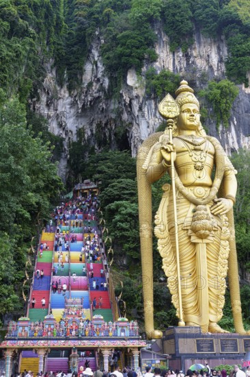 Murugan statue the God of War and colorful staircase leading to the caves with many pilgrims, Batu