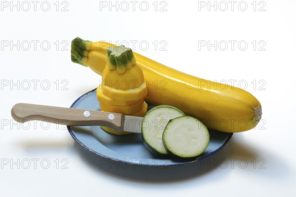 Green and yellow courgettes on a plate with a knife, Cucurbita pepo