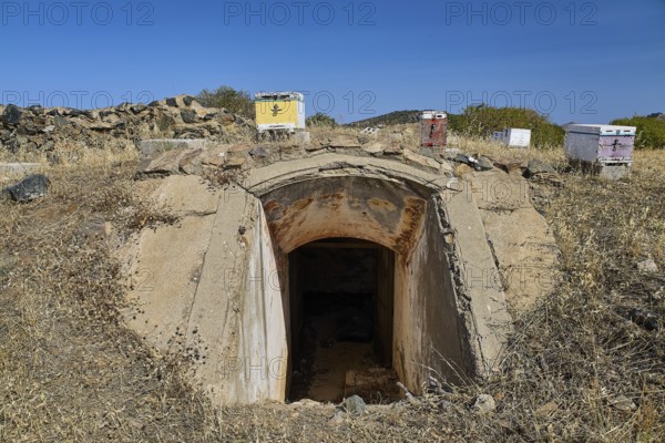 Lost Place, concrete bunker entrance in dry landscape under blue sky with vegetation, Italian air